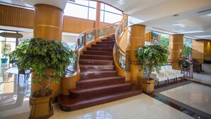 Una imponente escalera con barandillas de madera y plantas en macetas a ambos lados.