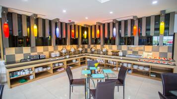 A modern dining area with a glass table, chairs, and a buffet setup.