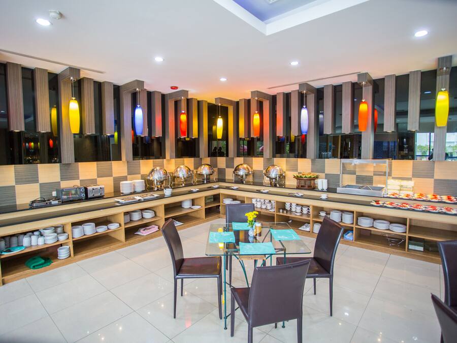 A modern dining area with a glass table, chairs, and a buffet setup.