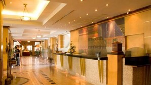 Zona de recepción de un hotel con mostrador de registro, suelo de baldosas e iluminación empotrada en el techo.
