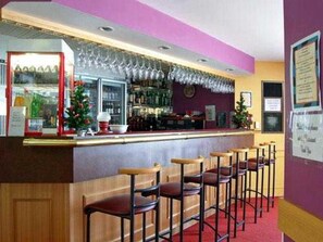 A bar area with a counter, multiple stools, and a Christmas tree decoration. - Centrepoint Motor Inn (Rockhampton)