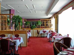 A restaurant with tables set for dining, a red carpet, and a view through a window. - Centrepoint Motor Inn (Rockhampton)