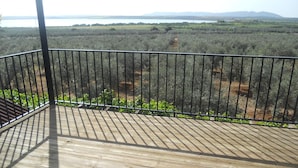 A wooden deck with a metal railing overlooking a landscape with trees and distant mountains. - Camping Rural Fuente de Piedra (Fuente de Piedra)