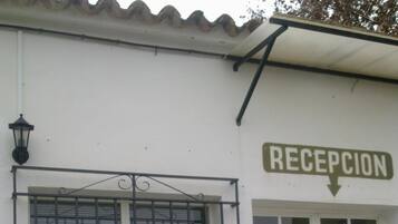A building with a sign reading "RECEPCION" and a window with metal bars.
