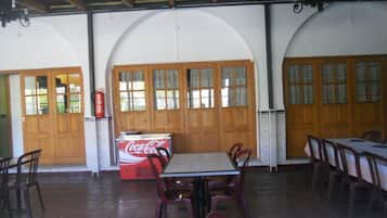 A dining area with wooden doors, a Coca-Cola cooler, and several tables and chairs.
