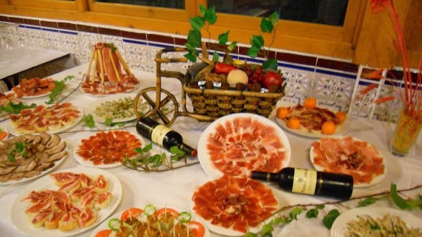 A table with various food items, including plates of sliced meats and vegetables, and a bottle of wine. - Camping Rural Fuente de Piedra (Fuente de Piedra)