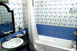 A bathroom with a sink, mirror, and bathtub.