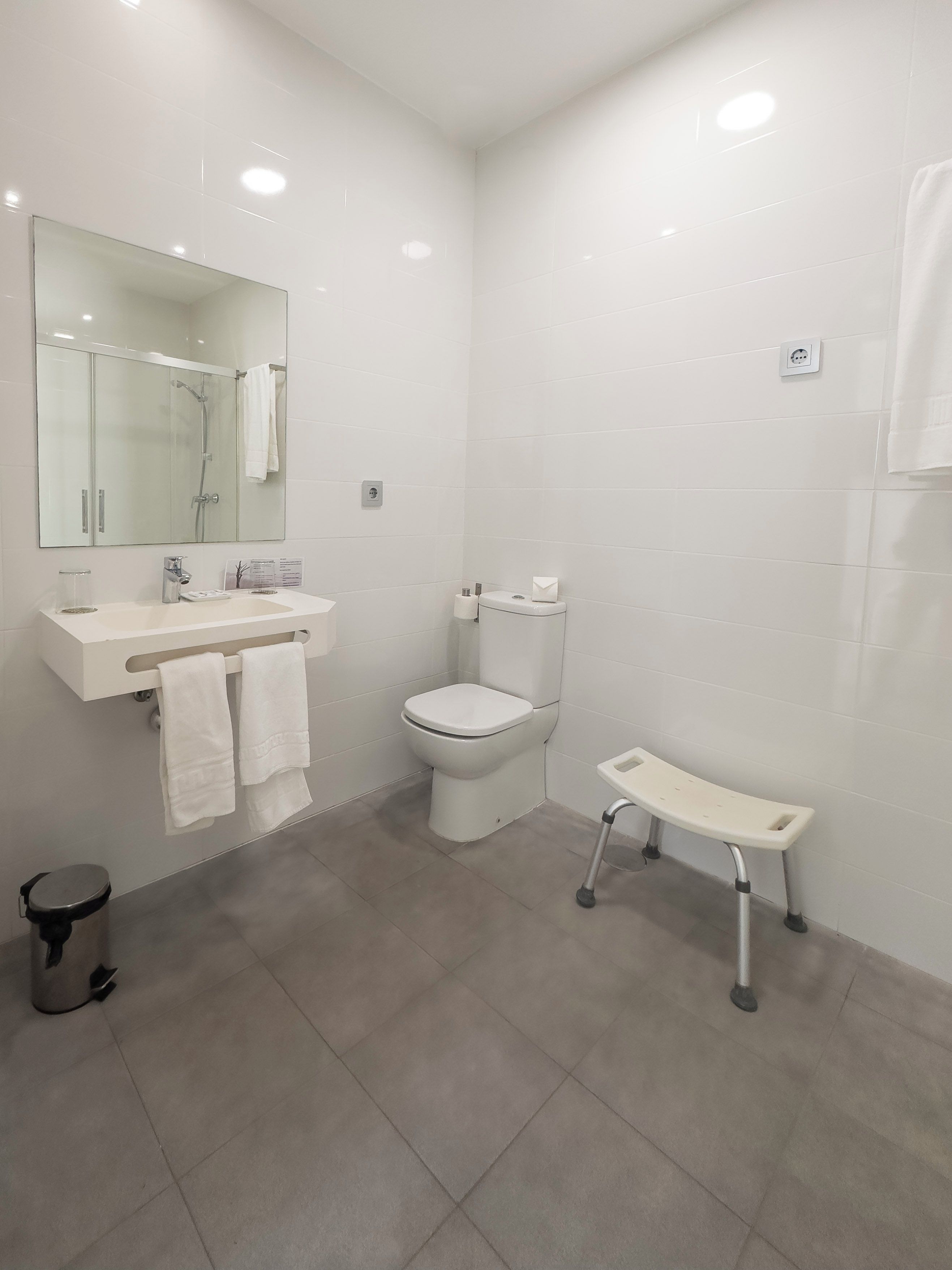 Un baño moderno con cabina de ducha de vidrio, inodoro blanco y tocador con espejo.