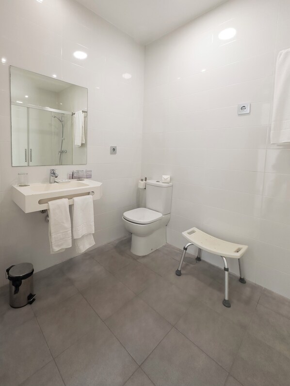 Un baño moderno con cabina de ducha de vidrio, inodoro blanco y tocador con espejo.