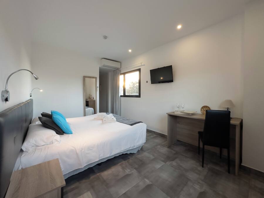 Habitación de hotel moderna con cama, escritorio y televisión.