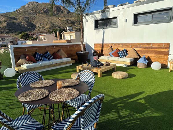 Un espacio al aire libre con mesa y sillas, un sofá y una pared de madera.