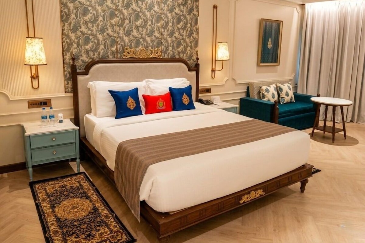 Ein Hotelzimmer mit einem großen Bett, einem Nachttisch, einem Beistelltisch, einem Sessel und einem kleinen Tisch.