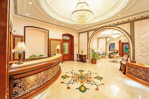 Eine Lobby mit einer Rezeption, einer Kristallleuchter und einem dekorativen Bodenmuster.