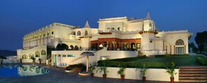 Ein großes, mehrstöckiges Hotel mit Pool, mehreren Balkonen und einem gepflegten Rasen.