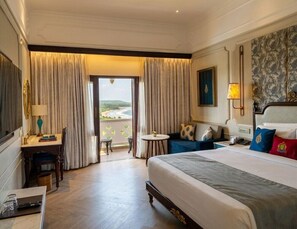 Ein Hotelzimmer mit einem großen Bett, einem Schreibtisch, einem Stuhl, einem kleinen Tisch und Blick ins Freie.