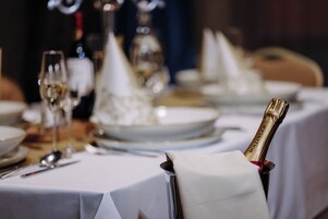 Una mesa dispuesta para una ocasión de cena formal, con una botella de champán y copas.