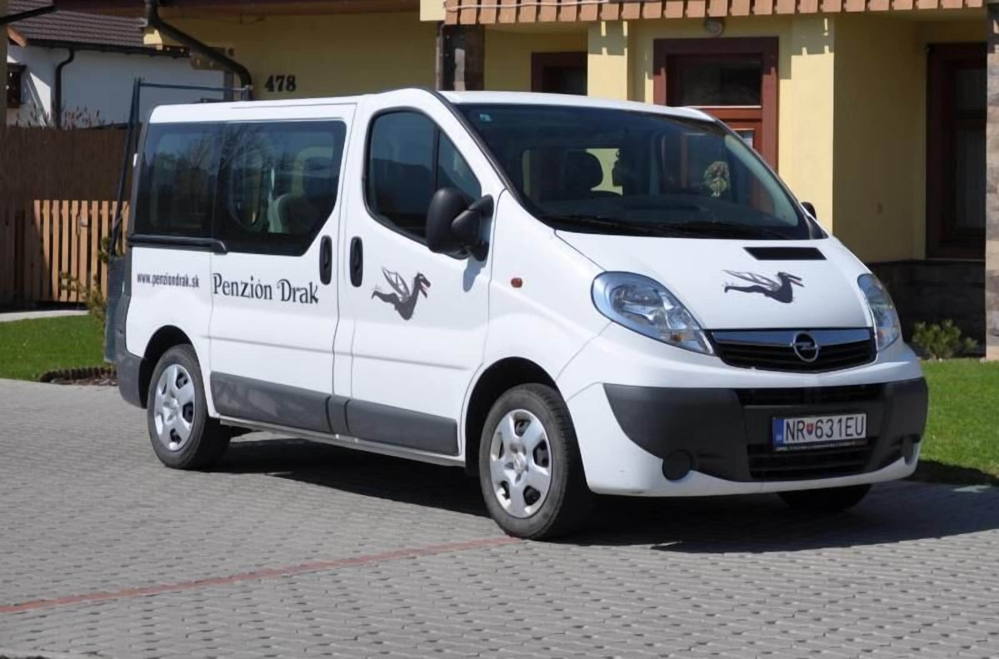 Una camioneta blanca estacionada frente a un edificio con el número 478 en la pared.