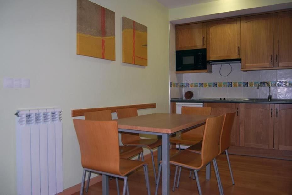 Un comedor con mesa y sillas, una cocina con armarios de madera y un salpicadero azulejado.