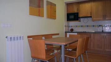 Un comedor con mesa y sillas, una cocina con armarios de madera y un salpicadero azulejado.
