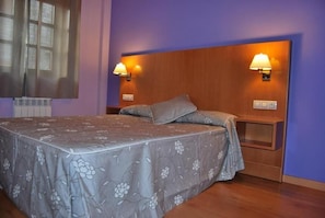 Un dormitorio con una cama, dos lámparas de pared y una mesita de noche.