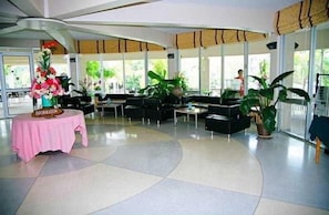 Un hall d’entrée spacieux doté d’un plafond incurvé, de grandes fenêtres et de plusieurs espaces aménagés pour s’asseoir.