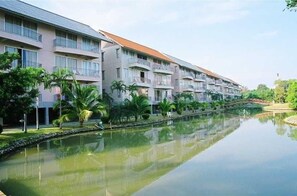 Un hôtel à plusieurs étages, doté de balcons, situé en bordure d’un canal et surplombant un pont.