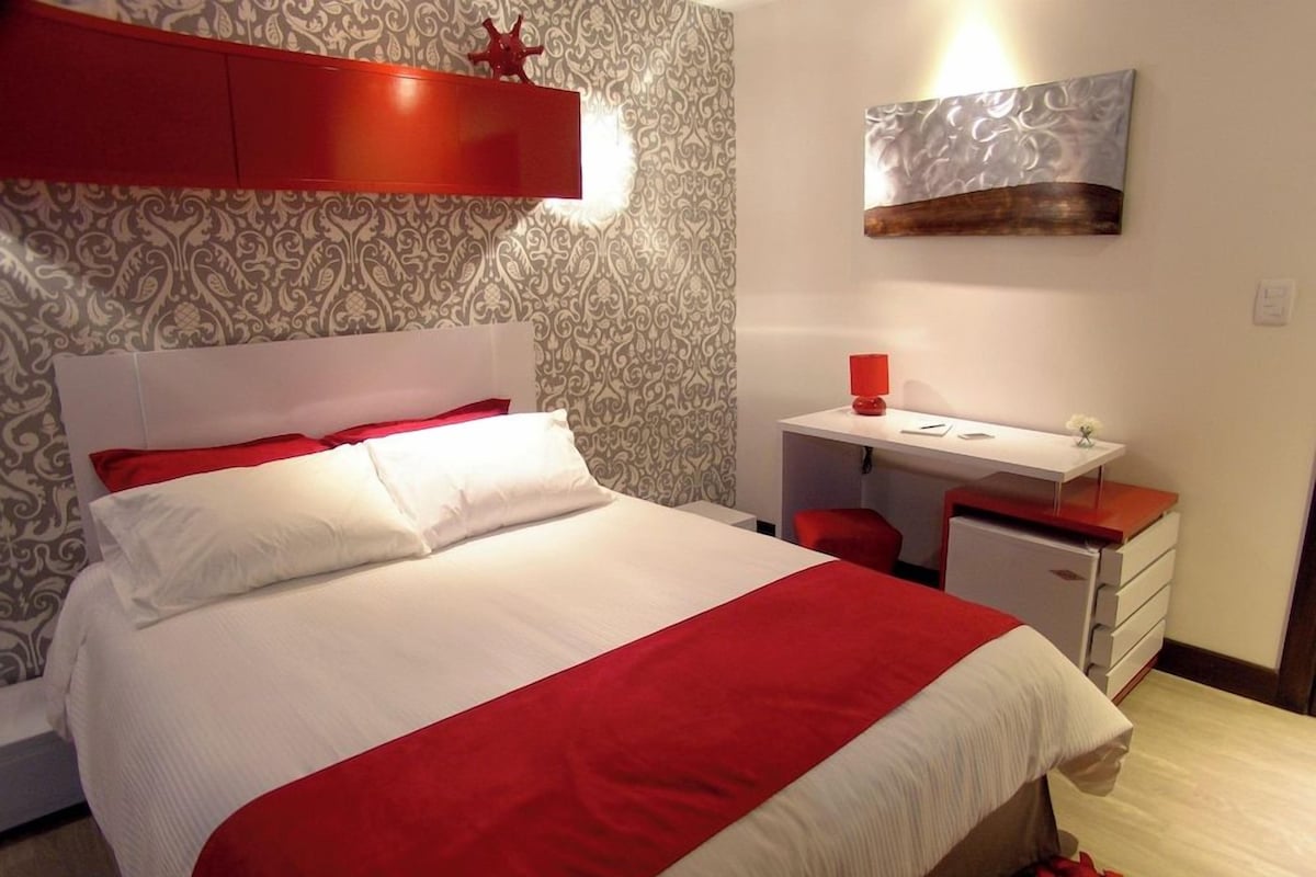 A bedroom with a bed, a desk, and a chair.