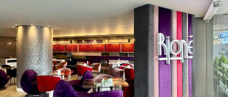 A modern interior with a prominent 'Rijone' sign, seating areas with purple and red chairs, and a patterned wall design.