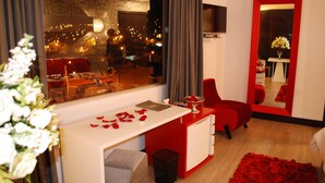A modern hotel room with a large window, a red desk, a mirror, and a red rug. - Rioné Hotel Boutique (Cuenca)