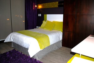 Un dormitorio moderno con una cama, una mesita de noche y una alfombra morada.