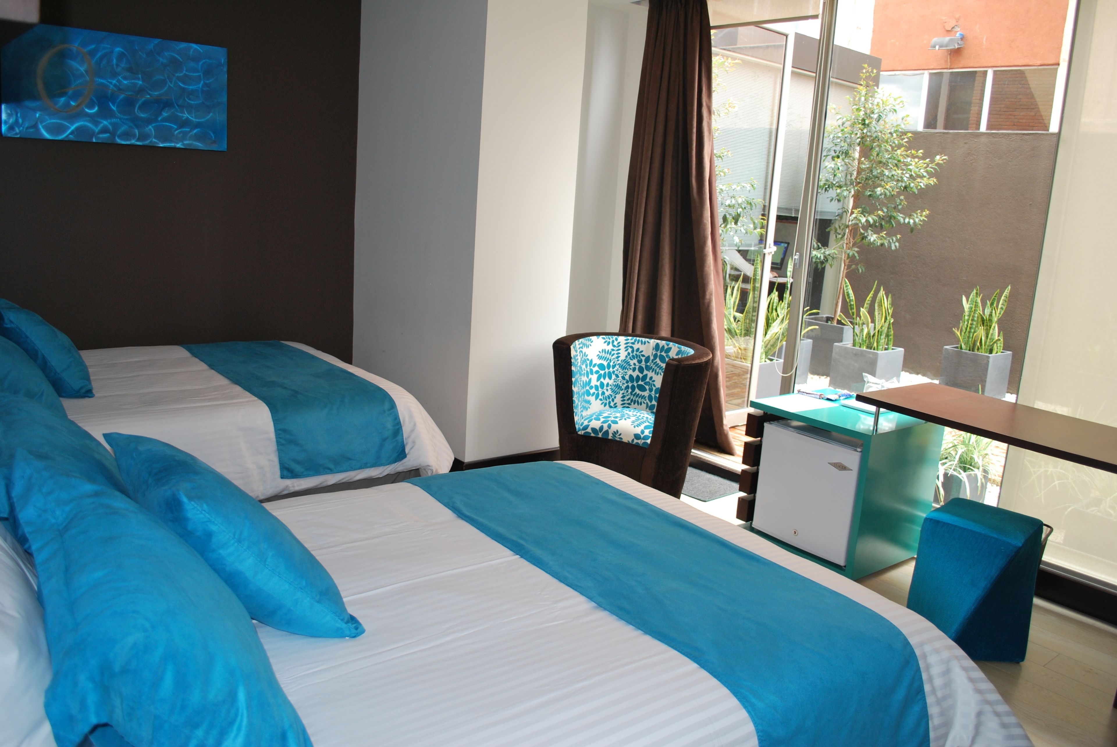 Una habitación de hotel con dos camas, un escritorio, una silla y vistas al exterior.