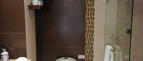 Un baño moderno con inodoro, lavamanos y cabina de ducha de vidrio.
