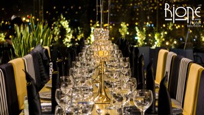 A formal dining table set with multiple wine glasses, plates, and cutlery, surrounded by upholstered chairs. - Rioné Hotel Boutique (Cuenca)