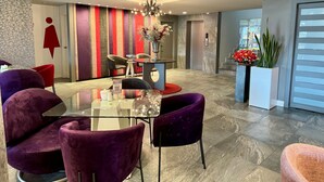 A modern dining area with a glass table, purple chairs, and a striped wall. - Rioné Hotel Boutique (Cuenca)