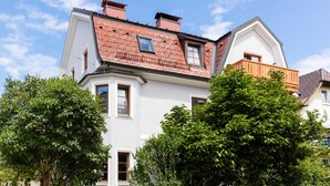 A two-story house with a red-tiled roof, white walls, and a balcony. - Villa Riedenburg Design Apartments (Salzburg)
