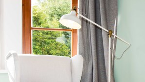 A white armchair with wooden legs, a red patterned pillow, and a white desk lamp. - Villa Riedenburg Design Apartments (Salzburg)