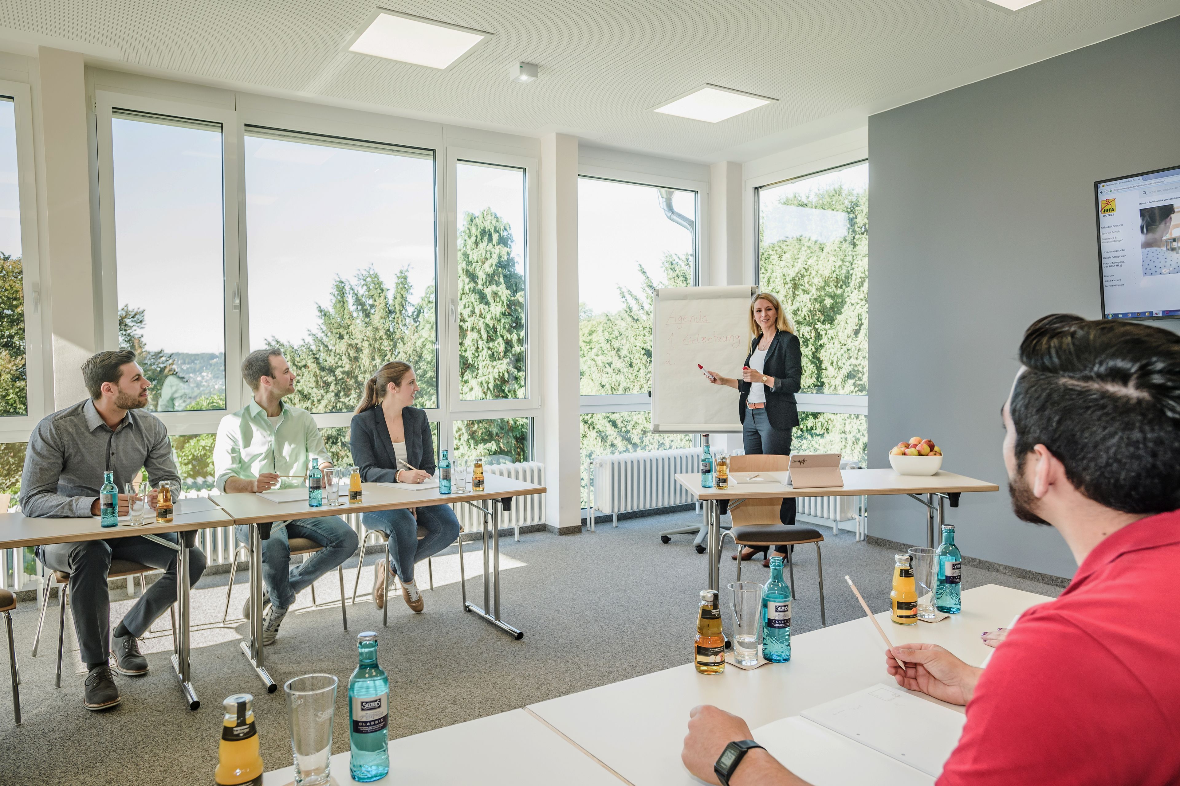 Une salle de réunion dotée de grandes fenêtres, d’un tableau blanc et d’un ordinateur portable posé sur une table.
