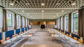 Ein Konferenzraum mit einem langen Tisch, Stühlen und einer Decke mit Rastermuster.