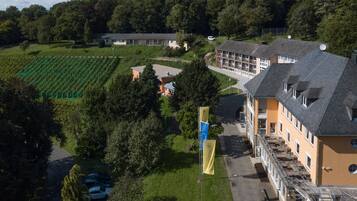 A hotel with a large building, a parking area, and a vineyard in the background.