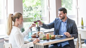 A dining table with a bottle of wine, cheese, bread, and a plant.