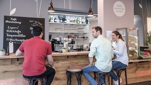 A bar area with stools, a chalkboard menu, and shelves with bottles and glasses.