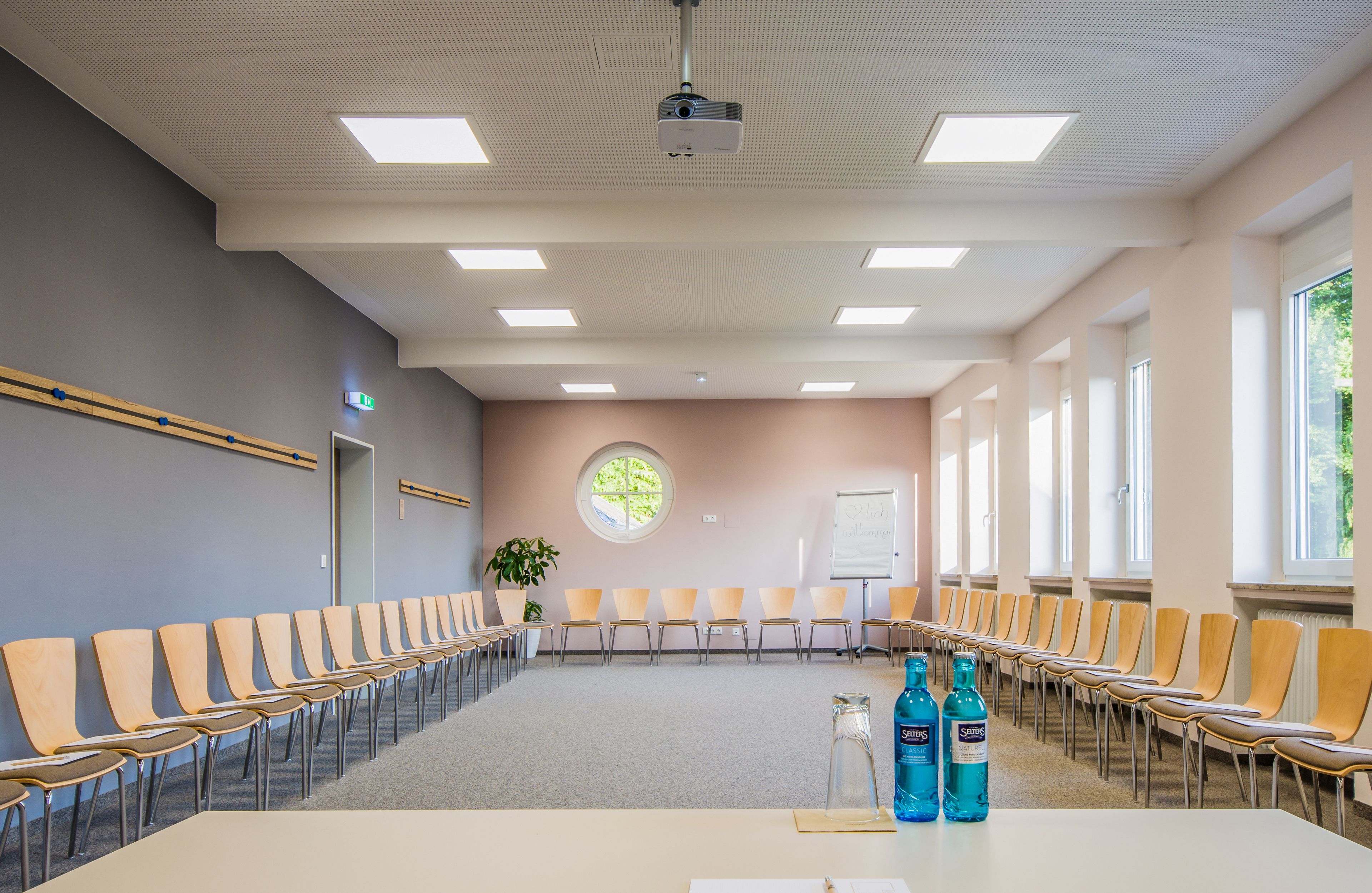 A conference room with a long table, chairs, a projector, and a whiteboard.