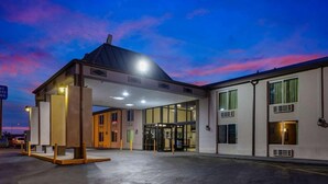 A hotel entrance with a covered waiting area, a glass door entrance, and a building with multiple windows and air conditioning units. - Motel6 Indianapolis, IN (Indianapolis)