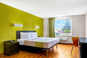 A hotel room with a bed, bedside tables, a desk, and a window with a view of the outside. - Motel6 Indianapolis, IN (Indianapolis)