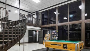 A pool table in a spacious indoor area with a spiral staircase and large windows. - Motel6 Indianapolis, IN (Indianapolis)