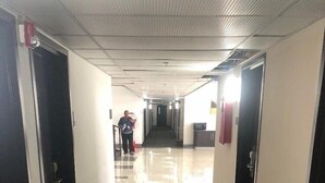 A hallway with carpeted floors, doors on both sides, and a person walking towards the end. - Motel6 Indianapolis, IN (Indianapolis)