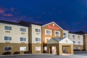 A multi-story Ramada hotel with a prominent sign, a parking lot, and a clear sky. - Ramada By Wyndham Coeur D'alene (Coeur d'Alene)