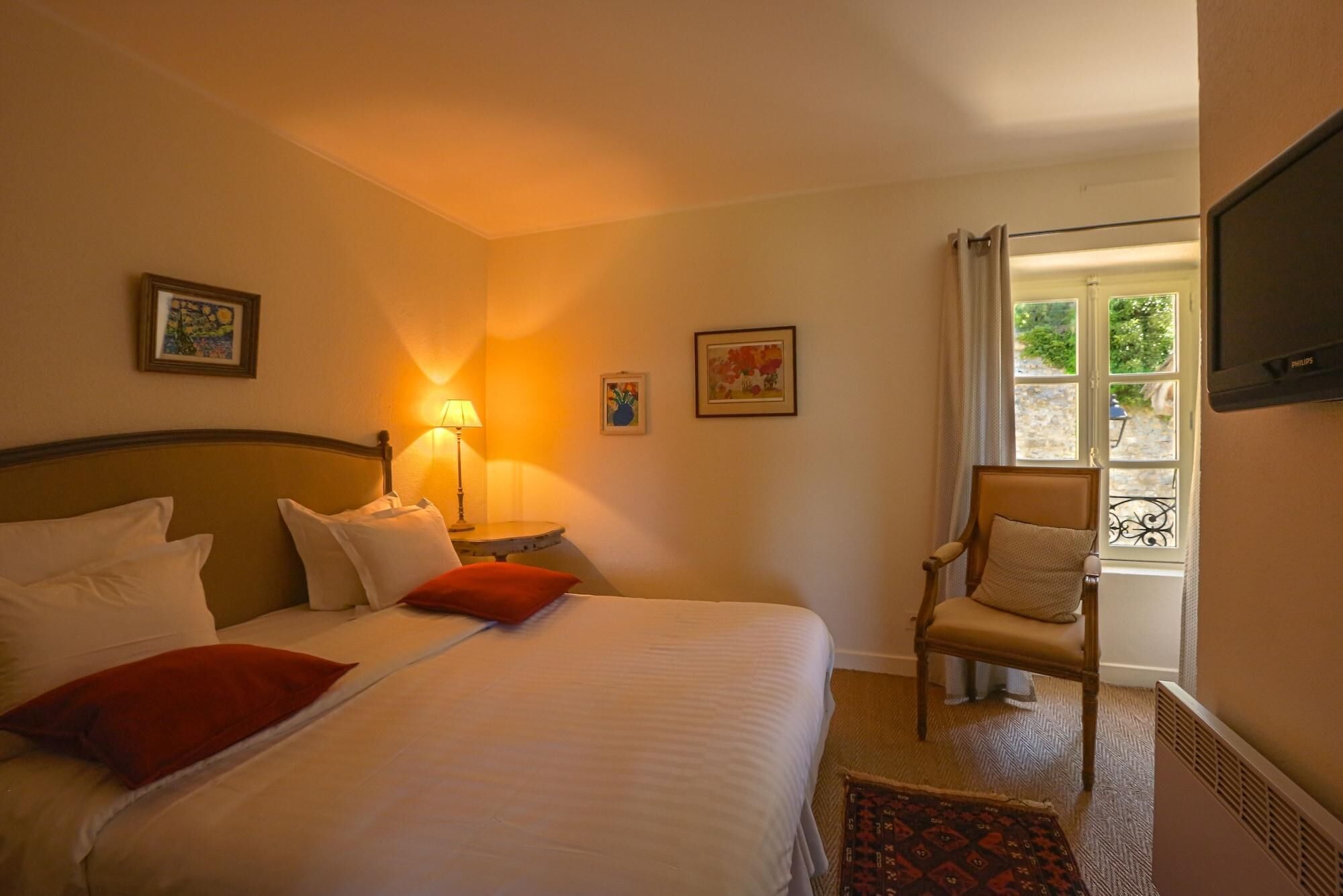 Una habitación de hotel con una cama, una silla, una lámpara y una ventana con vistas.