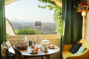 Una mesa de comedor con vistas al campo, una lámpara y una zona de estar acogedora con cojines.