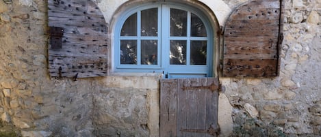 A stone wall with a wooden window and door, featuring a simple, rustic design.
